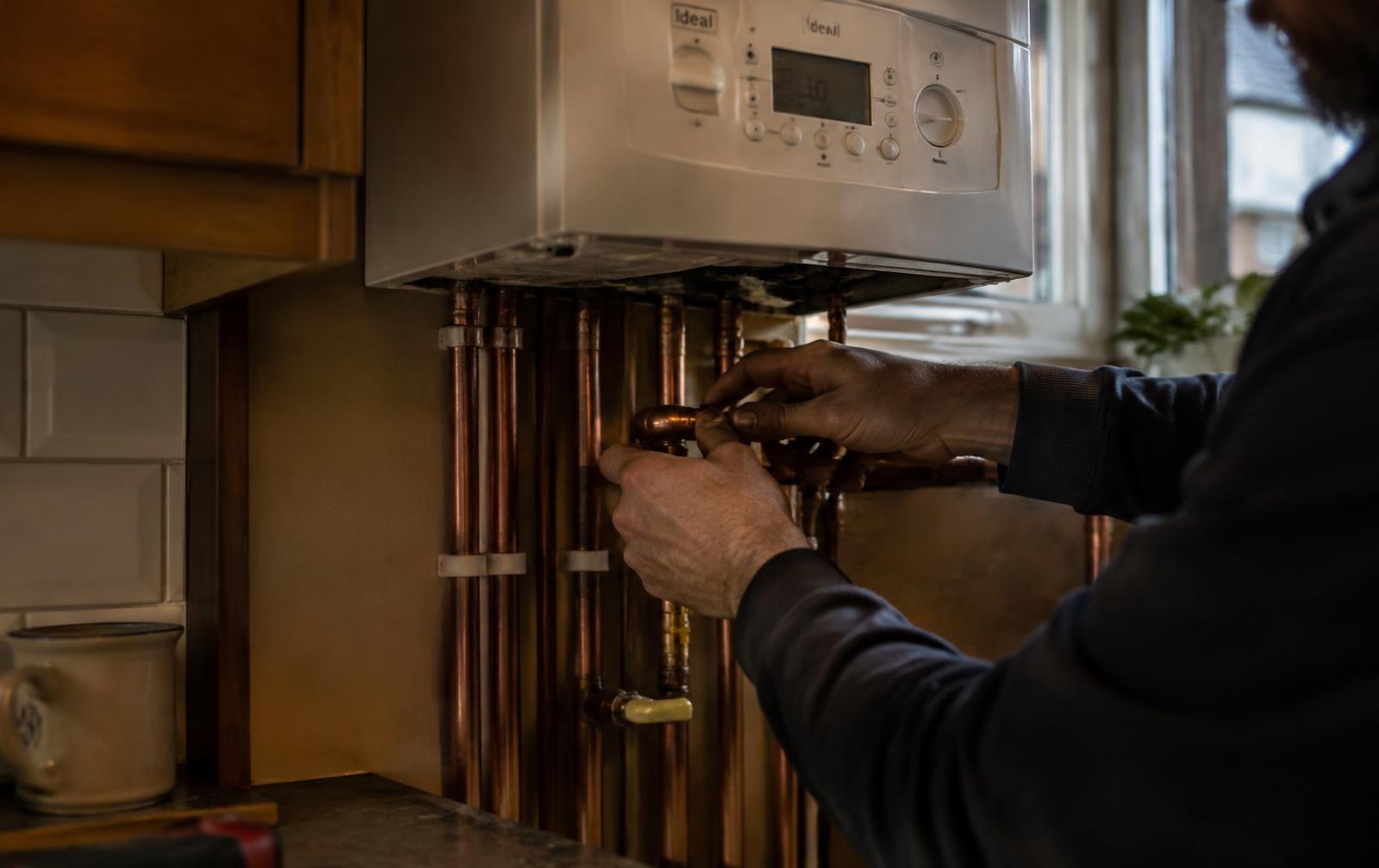 Gas engineer fitting boiler pipework in a Manchester home